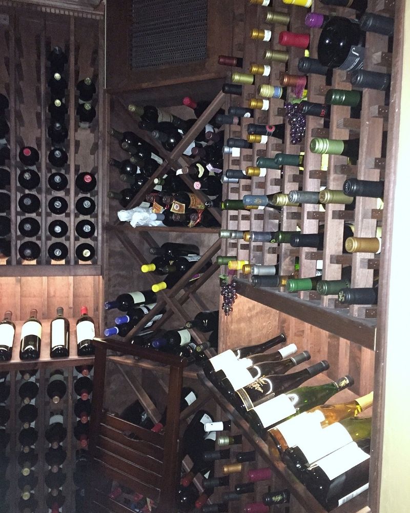Wooden wine cellar filled with assorted wine bottles, showcasing various labels and colors, creating an inviting atmosphere.