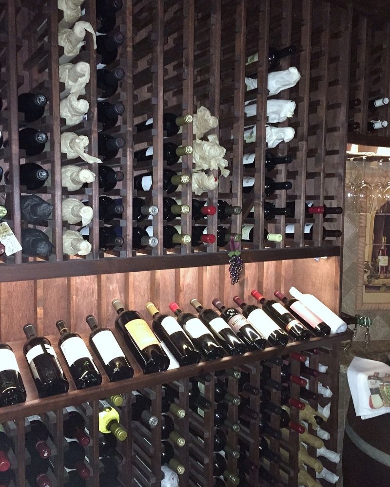 Alt text: A stylish wooden wine rack filled with various bottles of red and white wine, showcasing an organized collection.
