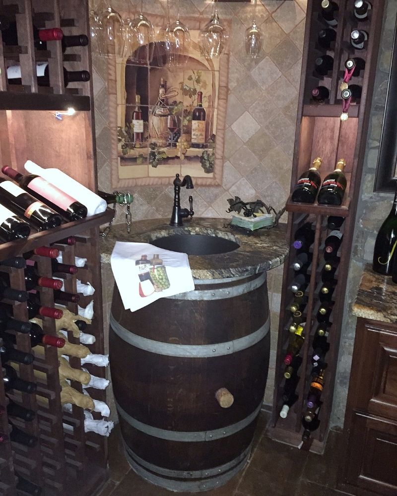 Home wine cellar featuring an elegant barrel sink, wine racks, and decorative art, perfect for wine enthusiasts.