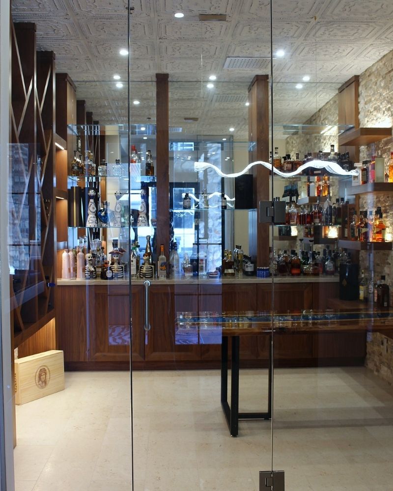 Modern home bar with an elegant design, featuring a wide selection of spirits displayed on glass shelves.