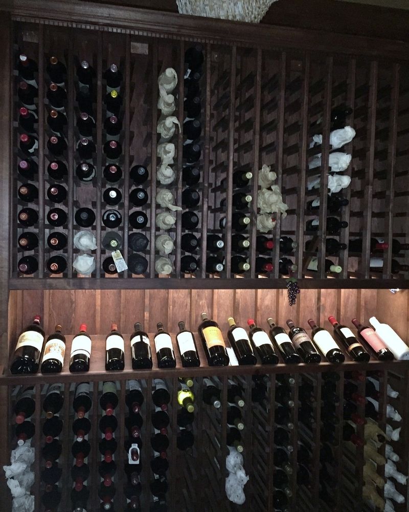 Wooden wine rack filled with various bottles of red and white wine, showcasing a well-organized wine collection.