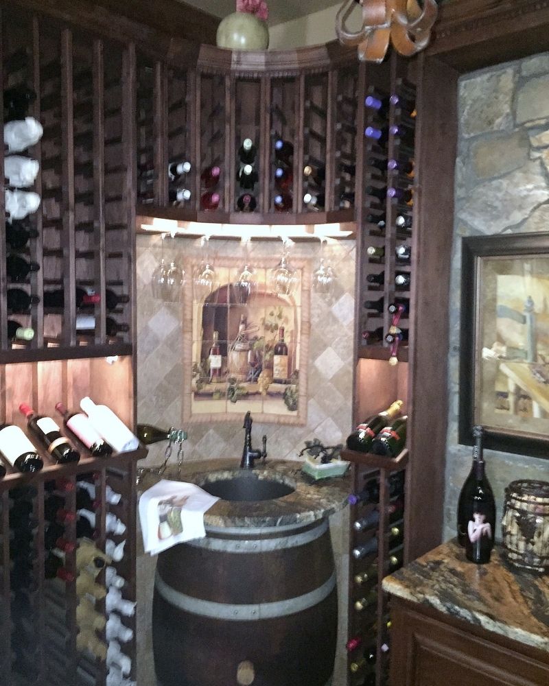 Elegant wine cellar featuring wooden racks, a granite counter, and decorative wine-themed art for wine enthusiasts.