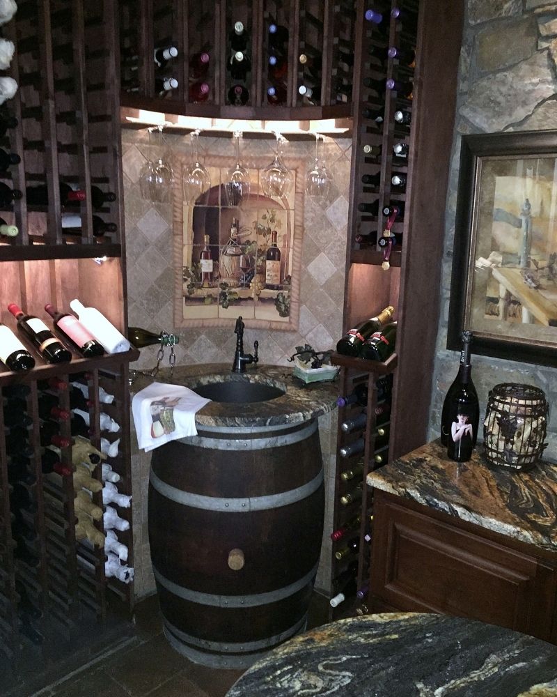 Rustic wine cellar featuring wooden racks, a barrel sink, and elegant decor, ideal for wine enthusiasts.
