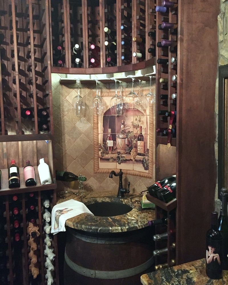 Cozy wine cellar with wooden racks, glasses hanging, and a granite countertop for wine tasting and storage.