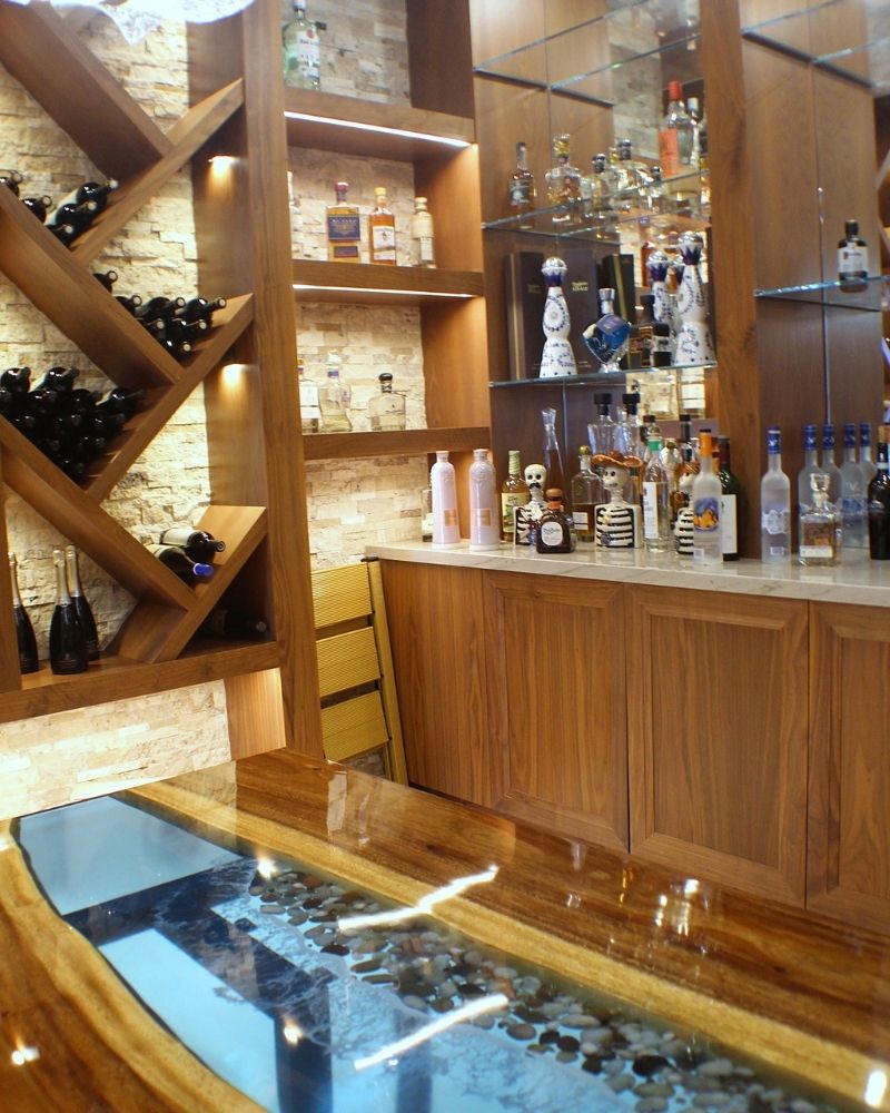 Elegant home bar featuring a wooden countertop, illuminated shelves, diverse liquor selection, and wine storage.