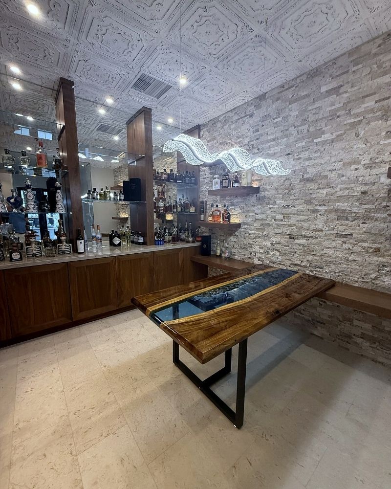 Completed Wine Cellar (42) Modern bar interior featuring a unique wooden table, stylish lighting, and a well-stocked liquor display in a chic setting.