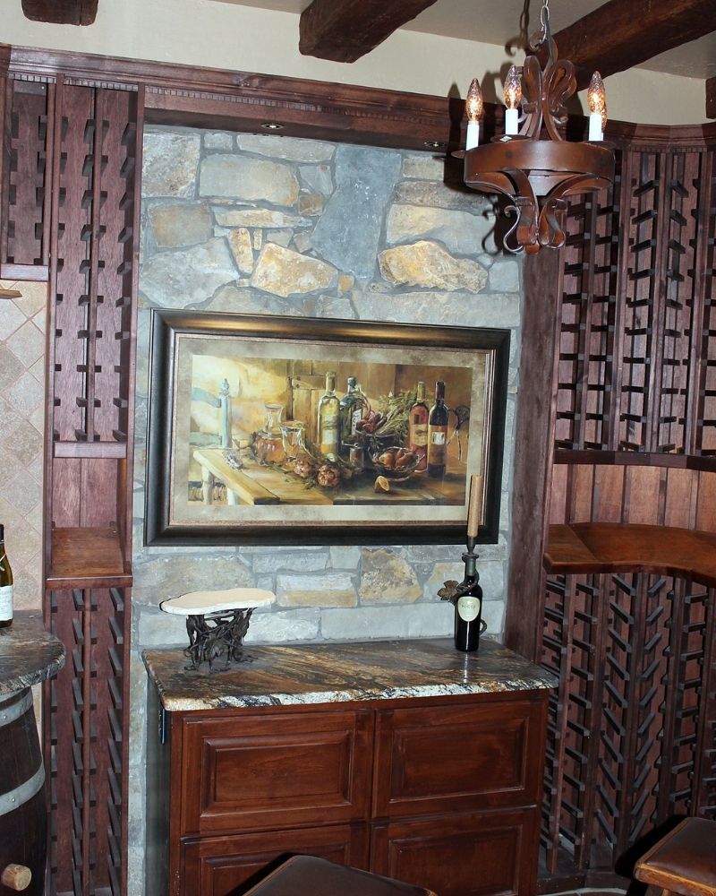 Cozy wine corner featuring stone wall, wood decor, and artwork of wine bottles on a granite countertop. Ideal for wine lovers.