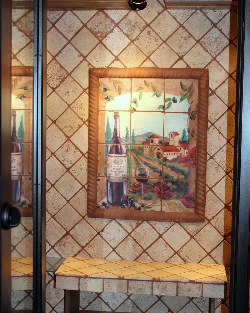 Artistic tile mural of a wine landscape framed in a rustic style against a textured wall. Cozy wine-themed interior decor.