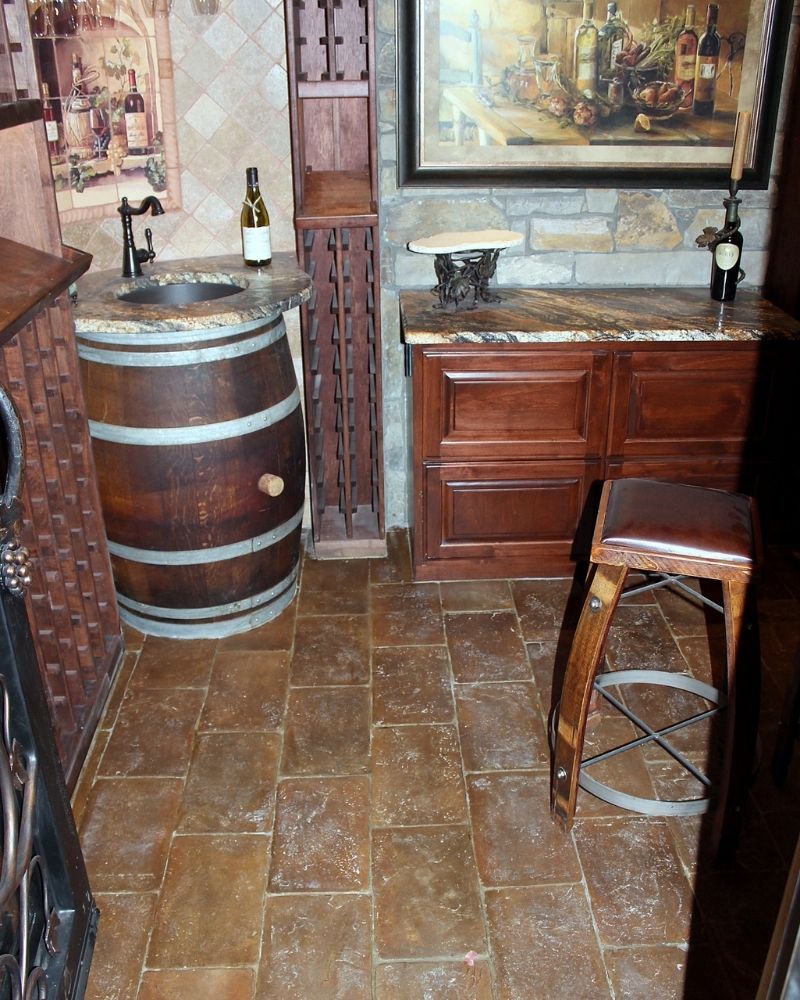 Elegant wine cellar interior featuring a wooden barrel sink, stone walls, and a rustic bar with vintage decor.