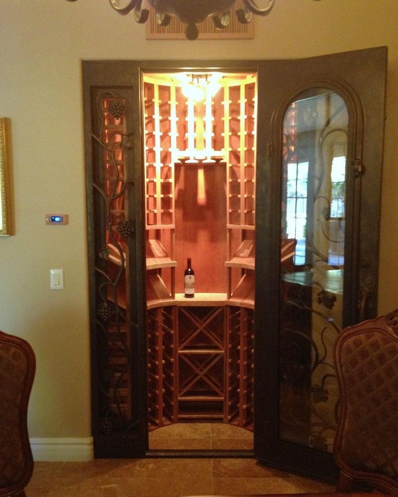 Elegant wine cellar with wooden racks, a bottle of wine on display, and ornate glass doors in a cozy home setting.