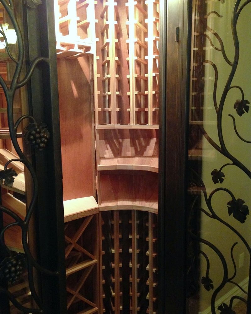 Elegant wooden wine cellar interior featuring custom racks and decorative wrought iron doors.