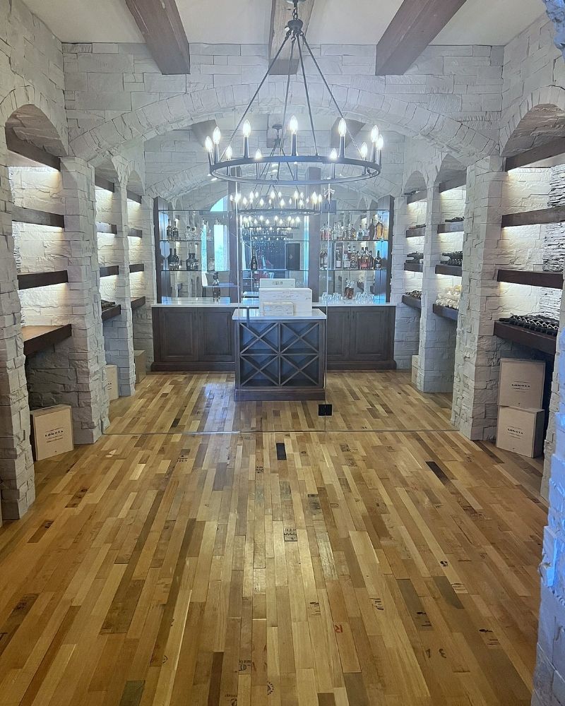 Completed Wine Cellar (55) Stylish wine cellar with stone walls, wooden floors, and elegant lighting, showcasing a modern design and expansive storage.