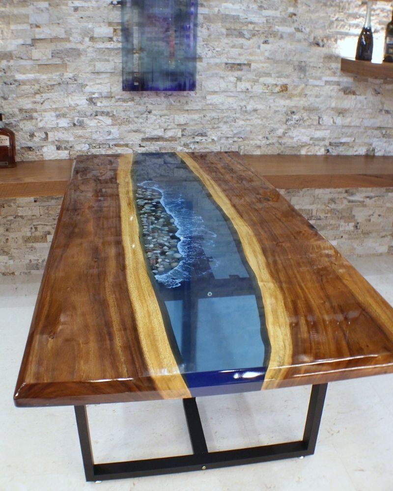 Stunning wooden dining table with a resin river design and glossy finish, showcasing natural stone accents.