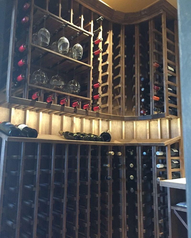Elegant wooden wine cellar showcasing bottles and glasses in a cozy, organized design for wine enthusiasts.