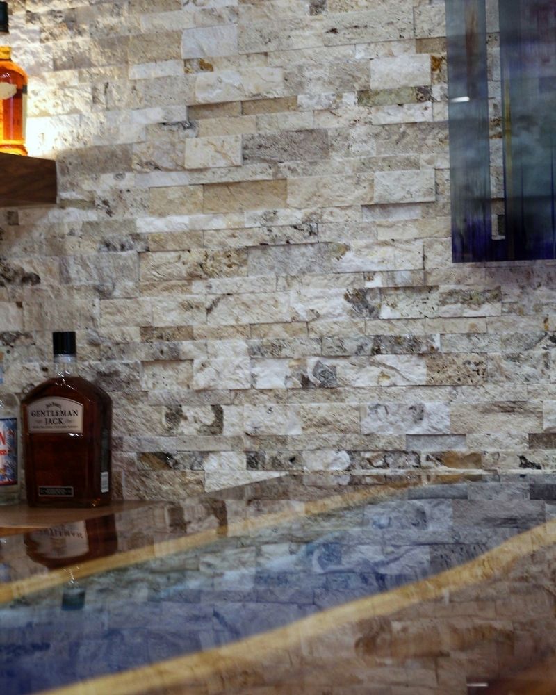 Stylish home bar setup featuring a textured stone wall, a sleek countertop, and premium whiskey bottles.