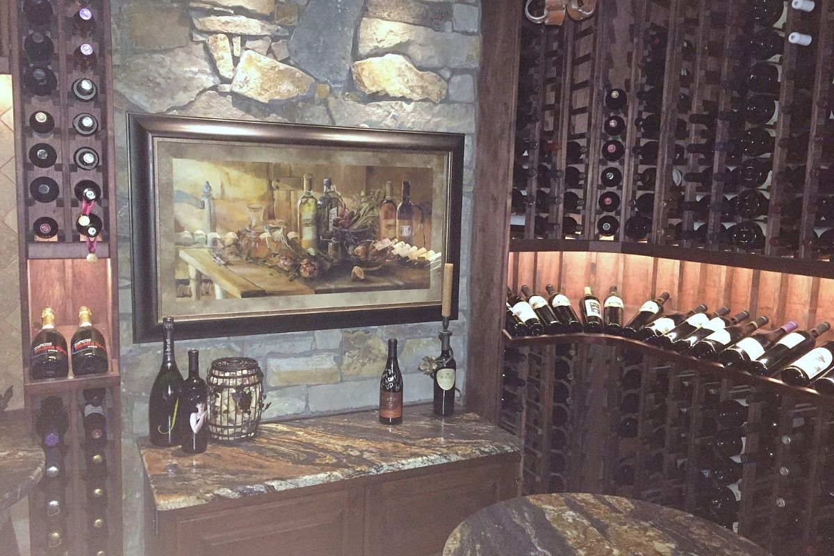 Luxurious wine cellar with rich wooden racks, a stone wall, and an elegant painting of wine bottles and grapes.