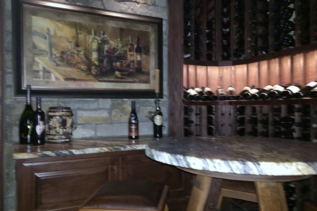 Cozy wine cellar featuring a rustic table, art, and an organized wall of wine bottles. Perfect for wine enthusiasts.