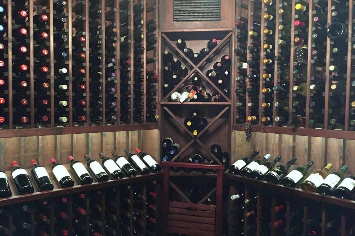 Wooden wine cellar filled with various bottles arranged neatly on racks showcasing a diverse wine collection.