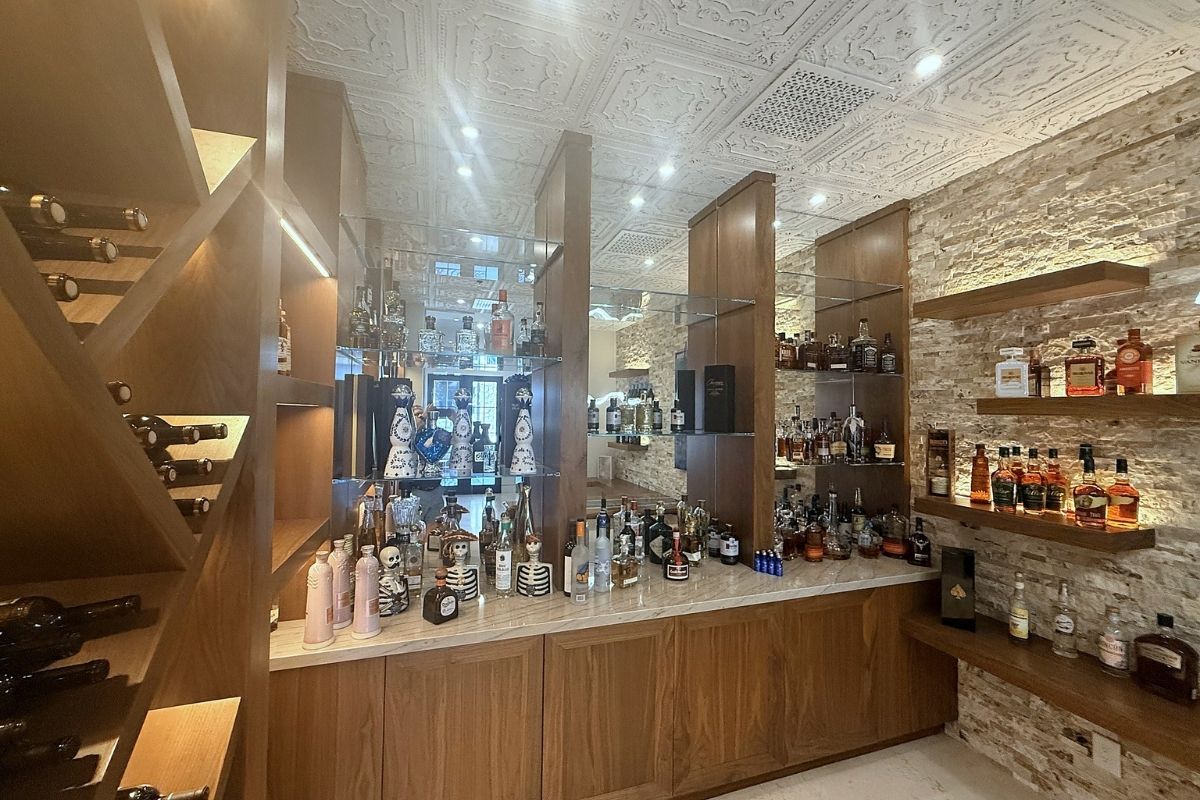Luxurious home bar with diverse liquor selection, elegant wooden shelves, and stylish interior design details.