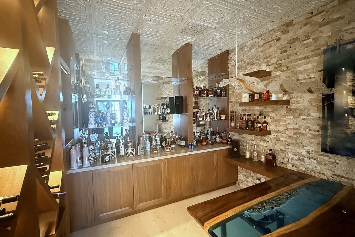 Stylish home bar featuring a wooden counter, shelves with assorted spirits, and elegant stone wall design.