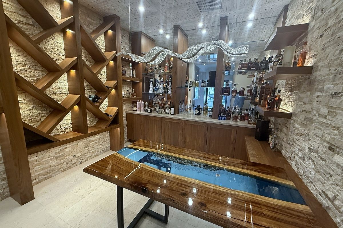 Stylish modern bar interior featuring elegant wood shelves, sparkling accents, and a unique resin river table.