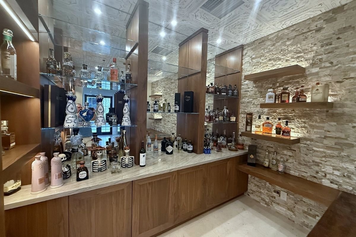 Elegant home bar featuring various liquor bottles, decorative skulls, and unique glassware on stylish wooden shelves.