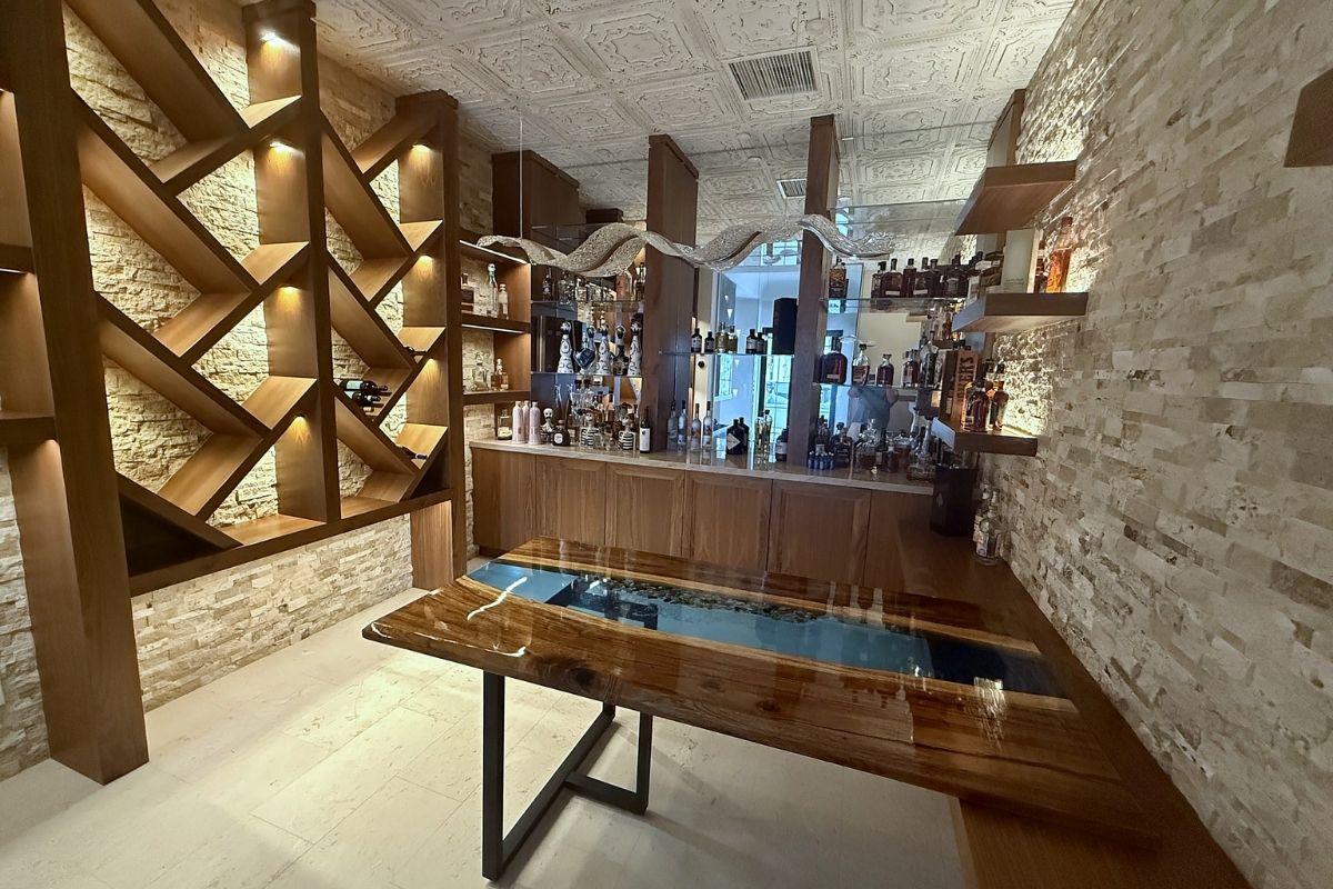 Modern home bar featuring a unique wooden table and stylish shelving with a variety of spirits and elegant decor.