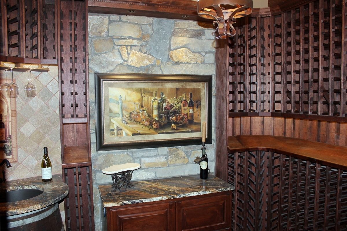 Elegant wine cellar featuring stone walls, wooden accents, artwork, and a marble countertop with wine bottles displayed.