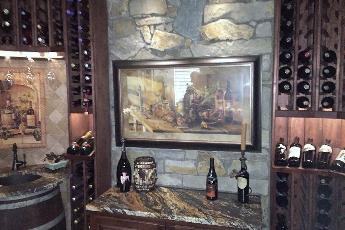 Elegant wine cellar with stone walls, wooden racks, assorted wines, and a vintage painting as a focal point.