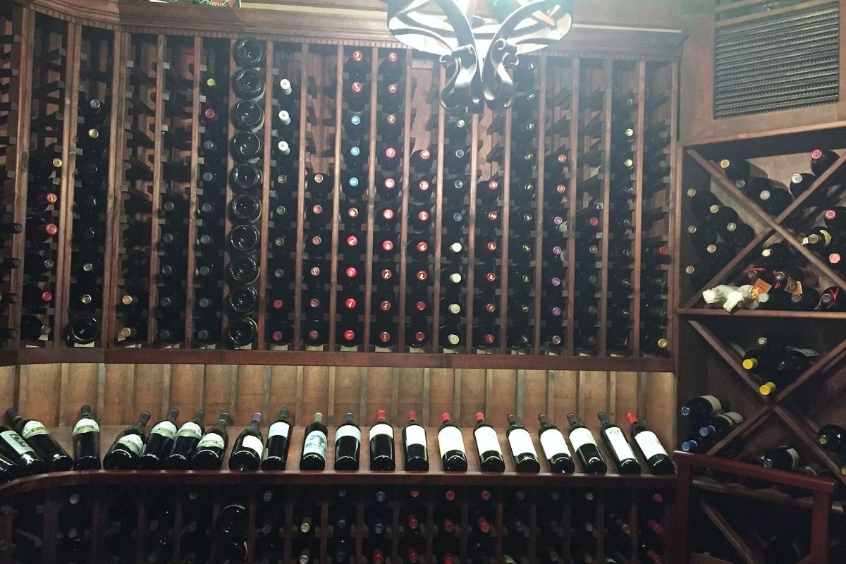 Wooden wine cellar filled with various bottles, showcasing a well-organized wine collection on multiple shelves.