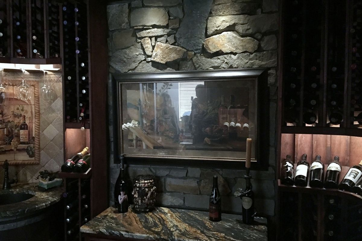 Cozy wine cellar featuring stone walls, art piece, wine bottles, and glasses, ideal for wine enthusiasts and collectors.