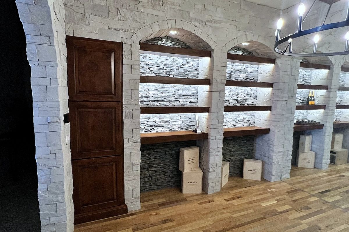 Stylish interior featuring stone archways, wooden shelves, and elegant lighting in a modern home or wine cellar.