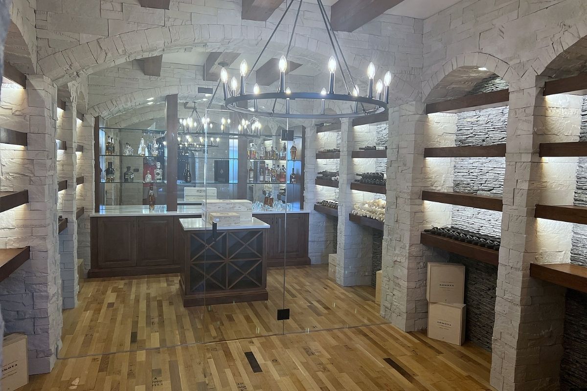 Elegant wine cellar featuring stone walls, wooden shelves, and a glass-front display for fine spirits and wines.