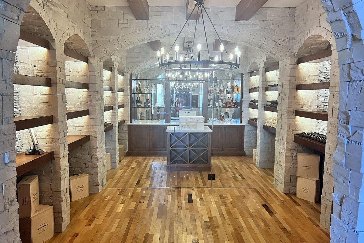 Elegant wine cellar featuring stone walls, wooden shelves, and a stylish bar area with ambient lighting. Perfect for gatherings.