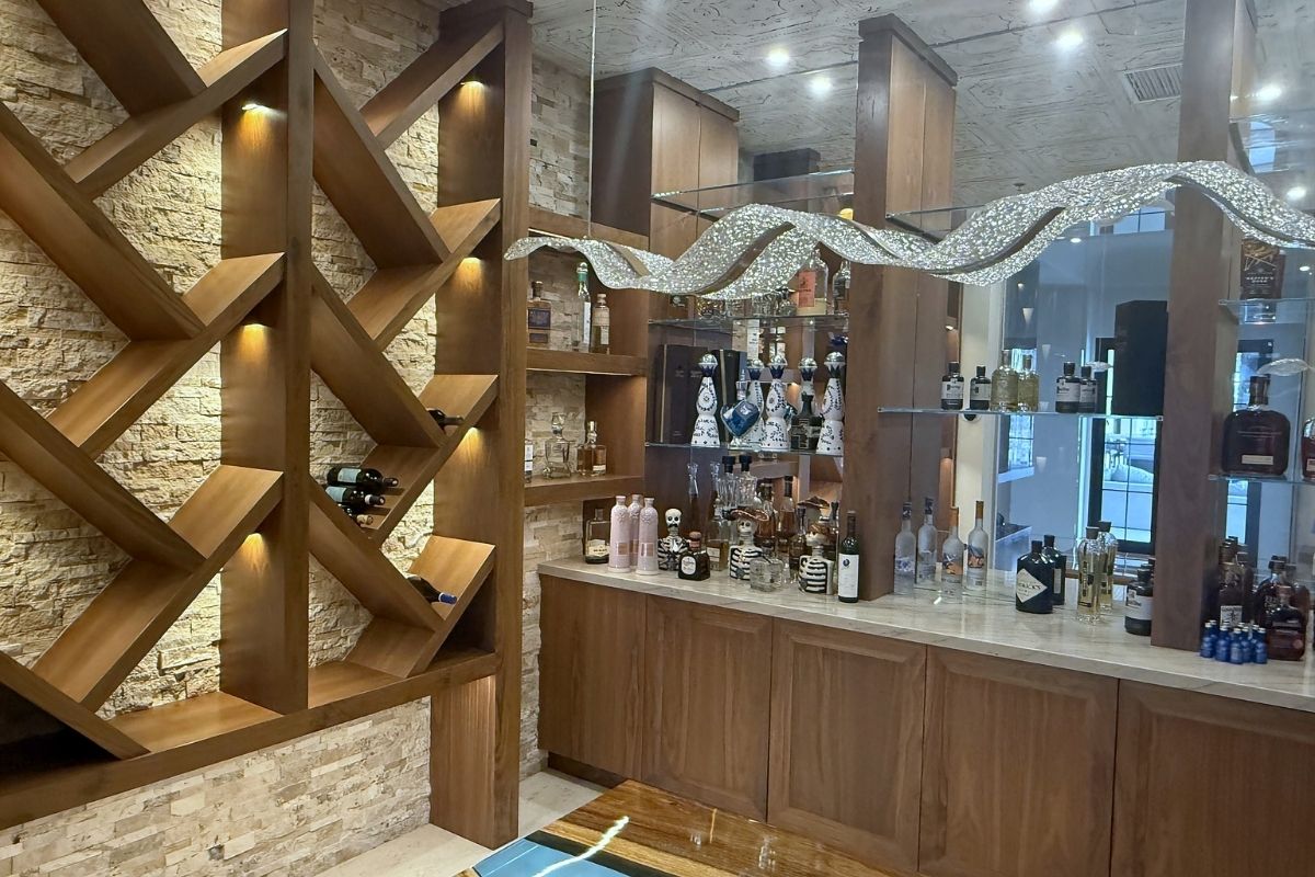 Stylish home bar with unique shelving, illuminated decor, and a variety of spirits and wine bottles on display.