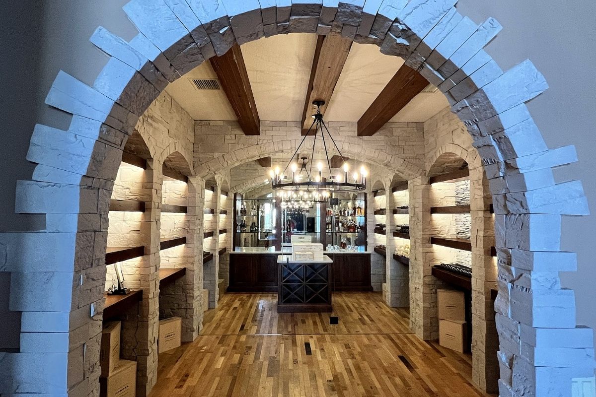 Elegant wine cellar featuring stone arches, wooden beams, and built-in shelves for bottles. Ideal for wine enthusiasts.