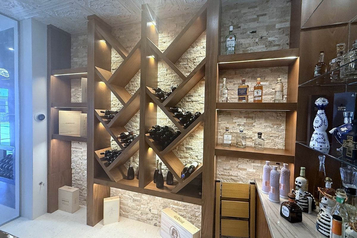 Elegant wine and liquor display with wooden racks and stone wall accents, showcasing various bottles and packaging.