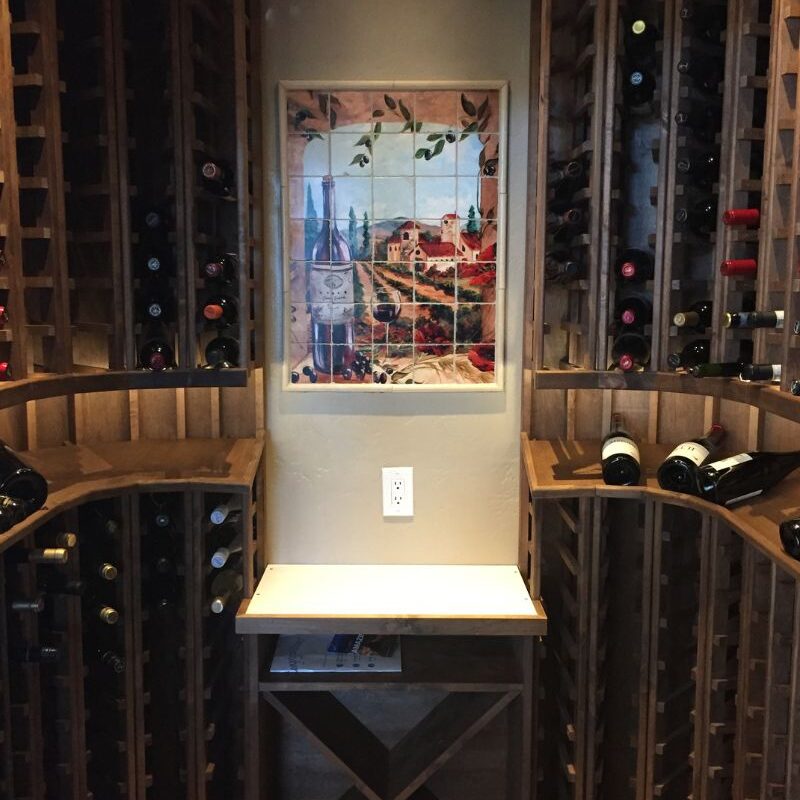 Alt text: Elegant wine cellar featuring wooden racks, a countertop, and a colorful wine-themed tile artwork.