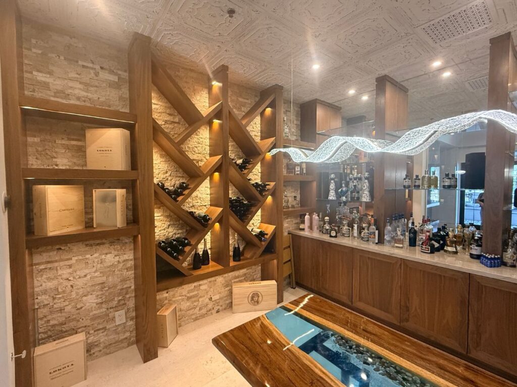 Modern wine cellar featuring elegant wooden shelving and a stylish bar with various bottles on display.