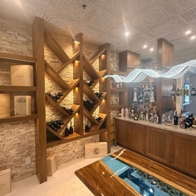 Modern wine cellar featuring elegant wooden shelving and a stylish bar with various bottles on display.