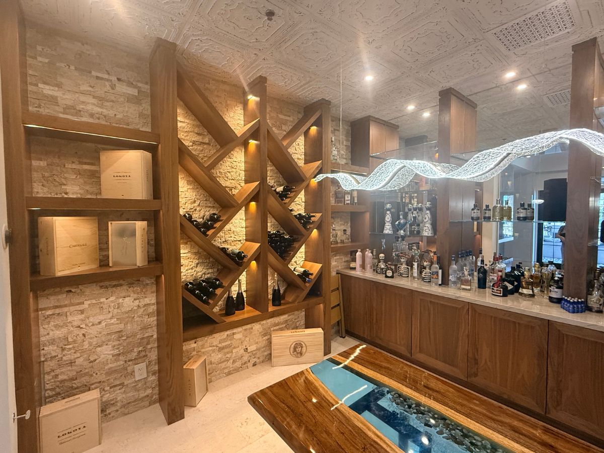 Modern wine cellar featuring elegant wooden shelving and a stylish bar with various bottles on display.